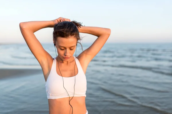 Sport fitness sporten vrouw op het strand luisteren naar muziek — Stockfoto