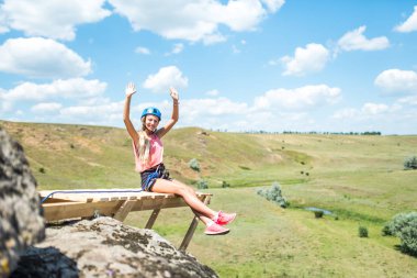 Yüksek bir dağ ve dağ manzara görünümü üzerinde ahşap bir çıkıntı üzerinde oturan kadın. Genç bir turist kadın dağlarda sahne sahiptir.
