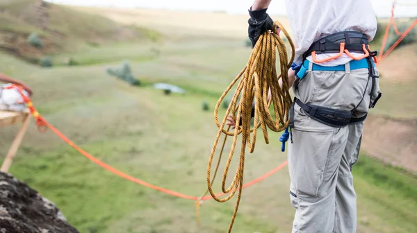 L'arrampicatore controlla l'assicurazione prima dell'uso, in piedi sulla cima di una montagna — Foto Stock