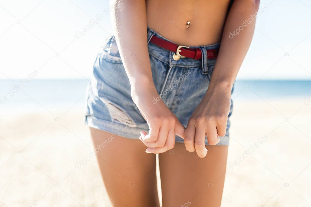 Woman showing her sexy curves. Hips and legs body part in short denim shorts.