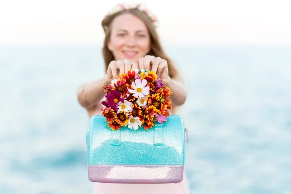 漂亮的女人与鲜花在海滩上快乐 图库图片