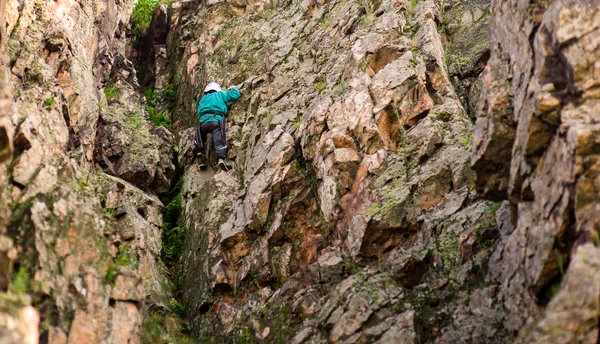 El niño en el casco sube a la roca, niño escalador deportes al aire libre . — Foto de Stock