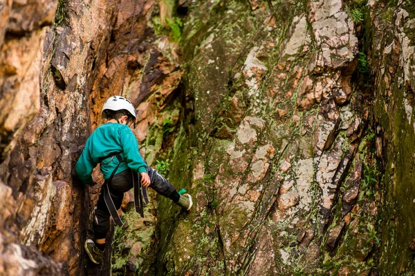 Il bambino col casco si arrampica sulla roccia, il ragazzo arrampicatore si arrampica all'aria aperta . — Foto Stock