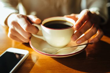 Ahşap arka planda el ele kahve içen bir kadın.