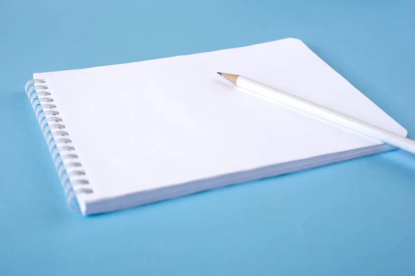 Um lápis e um caderno sobre fundo azul — Fotografia de Stock