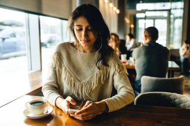 Kız kahve içiyor ve kafede müzik dinliyor