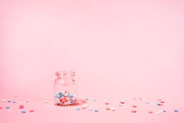 Pembe arka plan üzerinde küçük yıldız konfeti ile küçük şişe