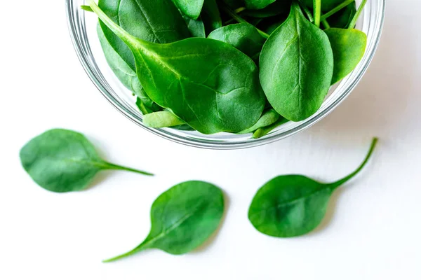 Beyaz masada cam kase taze yeşil ıspanak yaprakları.
