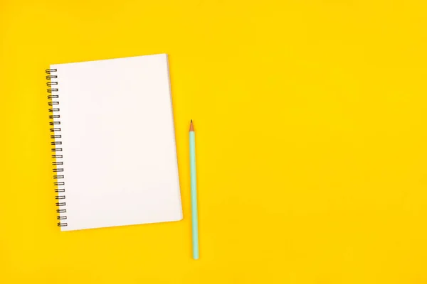 黄色の背景に空のノートと鉛筆、トップビュー. — ストック写真