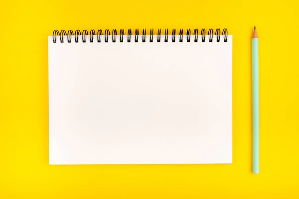 黄色の背景に空のノートと鉛筆、トップビュー. — ストック写真