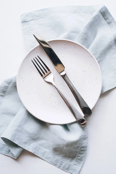 Um prato vazio e talheres em uma mesa branca. — Fotografia de Stock