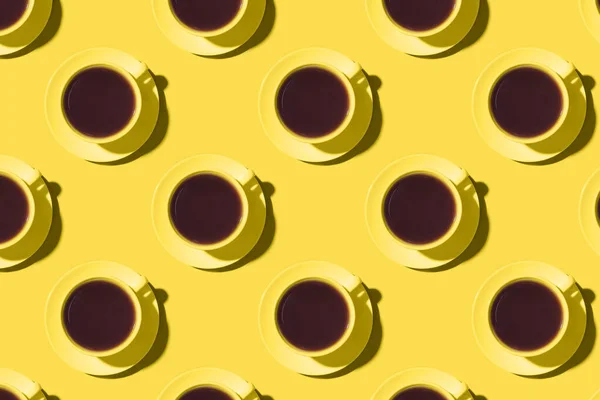 Muster von Tassen mit schwarzem Kaffee oder Tee auf gelbem Hintergrund. — Stockfoto