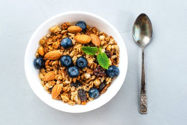 Gri arkaplanda yaban mersini ile pişirilmiş granola.