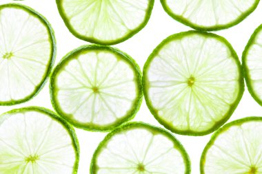 Beyaz arkaplanda yeşil limon dilimleri.
