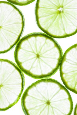 Beyaz arkaplanda yeşil limon dilimleri.