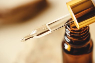 Doğal bej arka planda bir şişe kahverengi kozmetik..