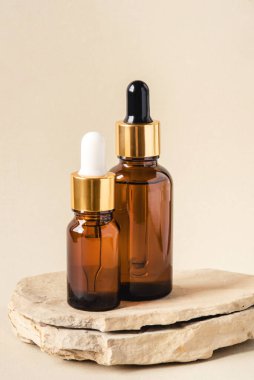 Doğal bej arka planda iki kahverengi kozmetik şişesi..