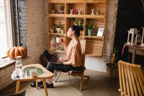 Giovane donna seduta con computer portatile in caffè — Foto Stock