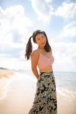 Muhteşem, mega mutlu Asyalı kız. Arka planda deniz dalgaları ve ufuk ile duygusal poz veriyor. Güneş gözlüklü güzel siyah saçlı kız mutluluğunu ifade ediyor..