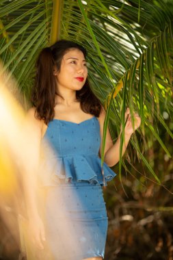 Muhteşem, mega mutlu Asyalı kız. Arka planda deniz dalgaları ve ufuk ile duygusal poz veriyor. Güneş gözlüklü güzel siyah saçlı kız mutluluğunu ifade ediyor..