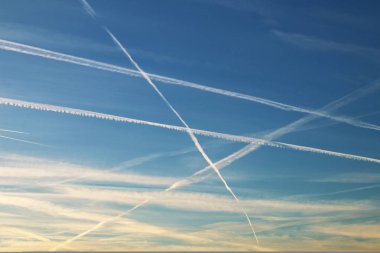 Chemtrails and airplane flying in the blue sky clipart