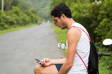 Bir akıllı telefon kullanarak güneş gözlüğü ile Kayıp genç turist. Seyahat Uygulaması Konsepti