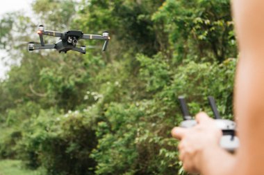 Odak ve bulanık eller üzerinde uçan drone bir alanda bir kontrol uzaktan adam tutarak