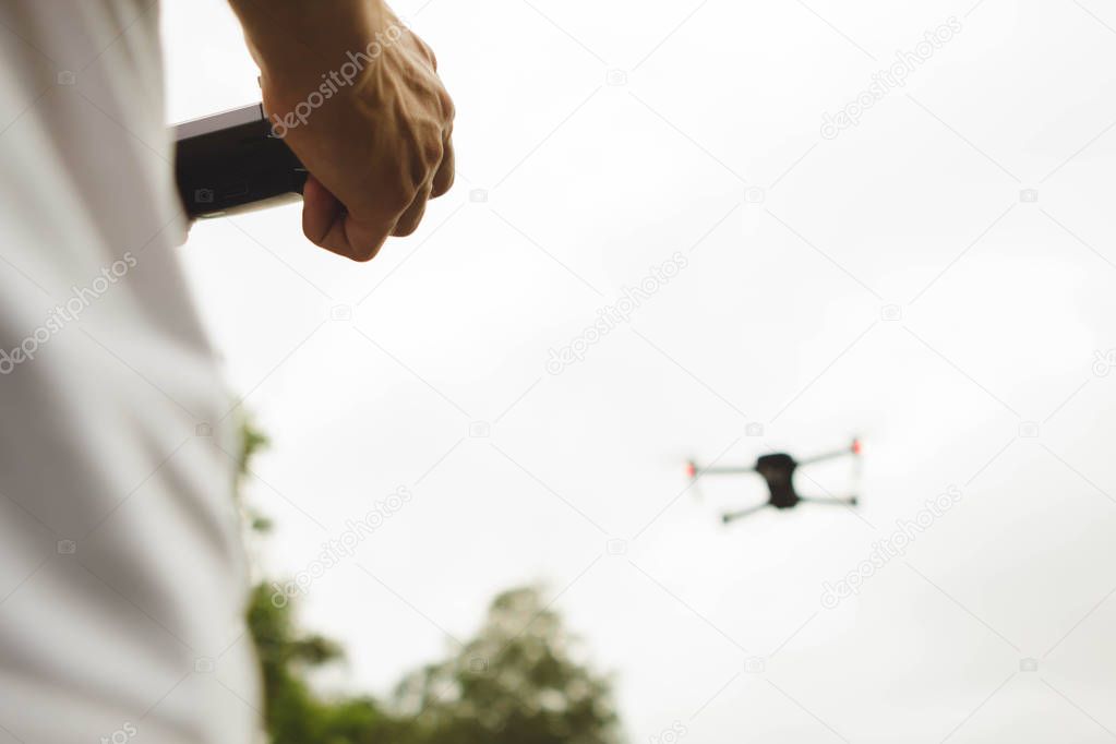 Back view of hands holding a remote control drone camera while flying in the sky