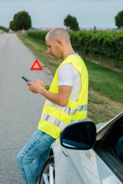 Genç adam seyahat ederken arabası ile yıkıldıktan sonra yol kenarında yardım çağrısı