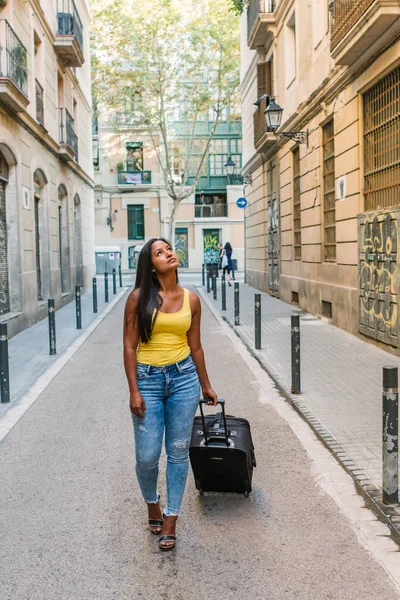 Latina ragazza turistica con valigia da viaggio è a piedi per strada e alla ricerca di un alloggio — Foto Stock