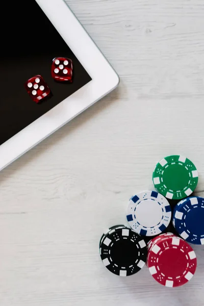 Poker chips and red dices on a tablet with space for text. Betting online and playing poker on internet