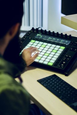 Sakallı genç DJ stüdyosunda elektronik müzik yapıyor.