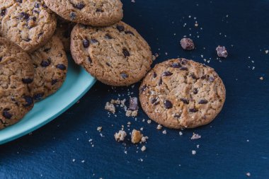 Geleneksel çikolatalı kurabiyeler ve yeşil tabakta kakao parçaları. Ön görünüm.