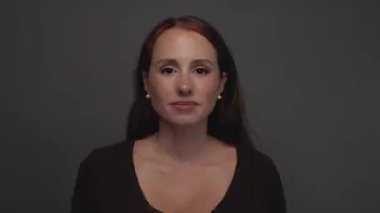 Kızıl saçlı, çilli ve kameraya ciddi ciddi bakan çekici bir kadının stüdyo resmi..