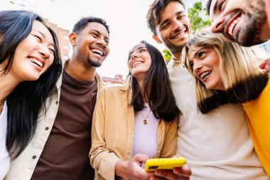 Mutlu arkadaş grubu şehir caddesinde cep telefonu kullanarak eğleniyor. Sosyal medya ve gençlik kavramı