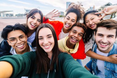 Bir grup genç öğrenci dışarıda telefonla selfie çektiriyorlar. Arkadaşlık yaşam tarzı ve gençlik toplumu kavramı