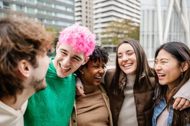 Genç bir grup insan dışarıda birlikte eğleniyor. Genç öğrenci arkadaşlar şehir caddesinde takılırken gülüyorlar. Birlik, gençlik ve dostluk kavramı