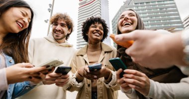 Mutlu genç arkadaş grubu şehirde cep telefonu kullanarak eğleniyor. Milenyum insanları cep telefonlarını tutarken gülüyor