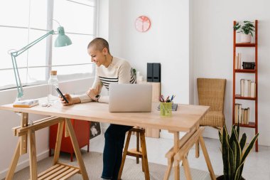 Ofiste çalışan mutlu bir iş kadını. Girişimci kadın iş yerinde cep telefonu kullanıyor.