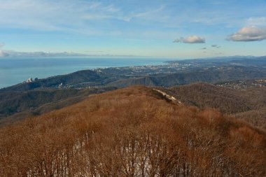 Karlı Dağları Panoraması. Kış orman ve deniz kenarında şehir. Güneşli kış günü. 