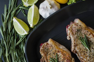 Rosemary ile dekore edilmiş bir tavada sebzeli ızgara biftek. Taze yeşillik. Marul, tatlı biber, roka ve biberiye dalları. Koyu arka plan. Yukarıdan görüntülemek.