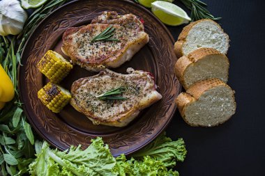 Rosemary ile dekore edilmiş bir tavada sebzeli ızgara biftek. Taze yeşillik. Marul, tatlı biber, roka ve biberiye dalları. Koyu arka plan. Yukarıdan görüntülemek.