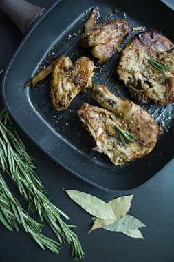 Bir ızgara tava, ızgara tavuk eti, biberiye, karanlık bir arka plan üzerinde sebze için baharat ile dekore edilmiş. Yukarıdan görüntülemek