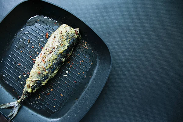 Macrou prăjit într-o tigaie de grătar, decorat cu condimente pentru pește. Fundal întunecat. Locul pentru teskta. Vedere de sus . — Fotografie, imagine de stoc