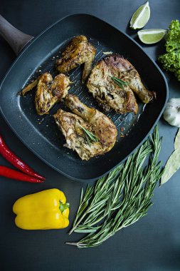 Bir ızgara tava, ızgara tavuk eti, biberiye, karanlık bir arka plan üzerinde sebze için baharat ile dekore edilmiş. Yukarıdan görüntülemek