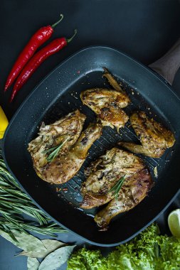 Bir ızgara tava, ızgara tavuk eti, biberiye, karanlık bir arka plan üzerinde sebze için baharat ile dekore edilmiş. Yukarıdan görüntülemek