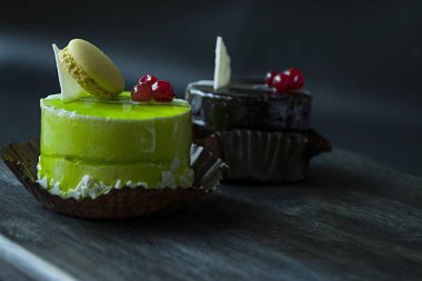 Lezzetli pasta. Küçük bir çikolatalı kek, çikolata ile kaplı ve kartopu, siyah bir arka plan üzerinde giyinme şekerlemeler ile dekore edilmiştir. Yan görünüm