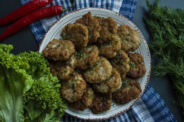 Domuz pirzola Yeşiller ve sebze siyah bir arka plan ile bir tabakta. Yukarıdan görüntülemek.