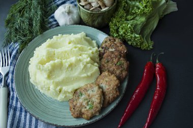 Domuz pirzola patates püresi, yeşil ve siyah bir zemin üzerine taze sebze ile. Yukarıdan görüntülemek.