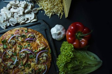 Sosis, domates, mantar ve peynir karanlık bir arka plan üzerinde taze pizza. Taze sebze ve baharatlar ile dekore edilmiştir. Yukarıdan görüntülemek.